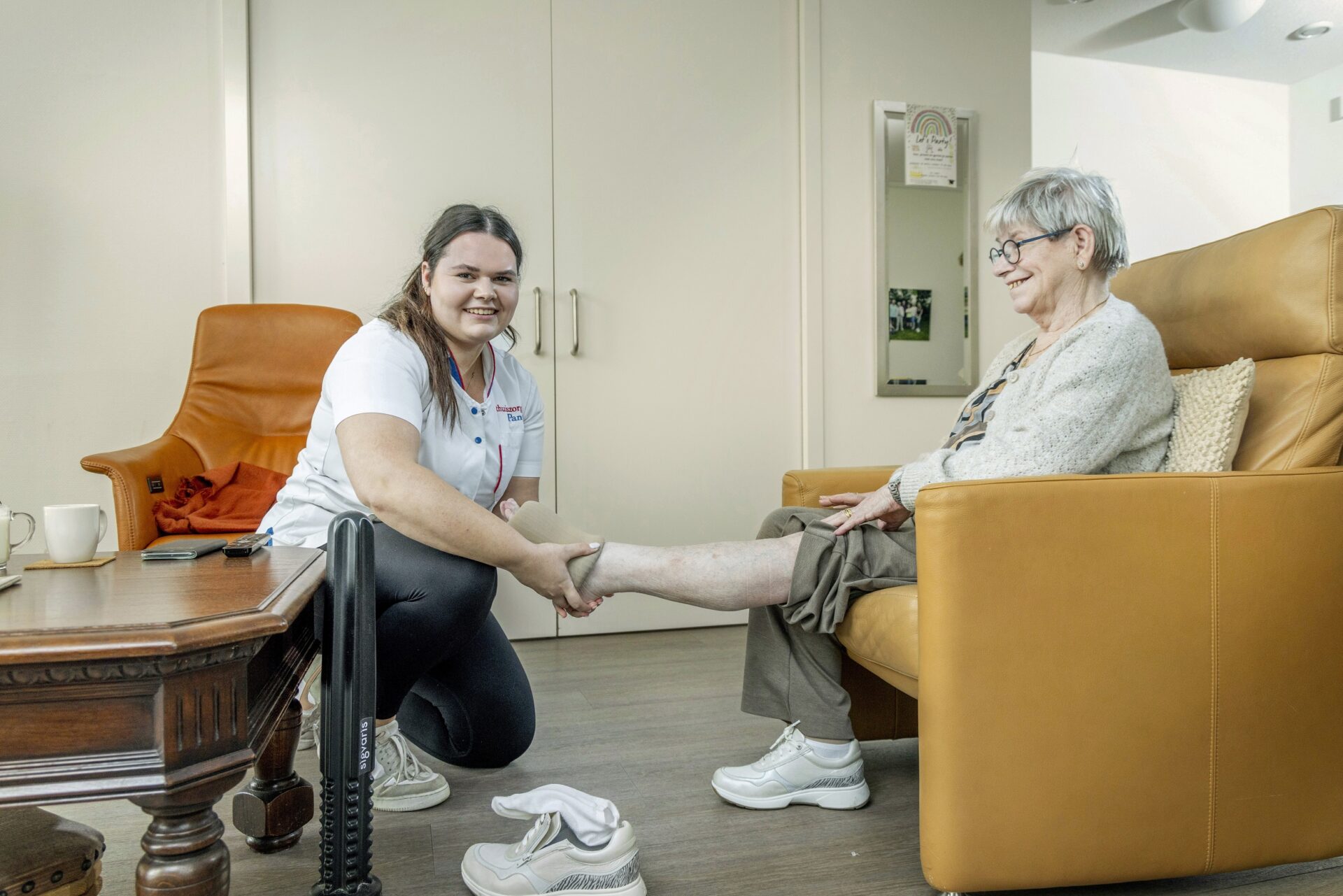 Verpleegkundige trekt cliënt steunkousen aan